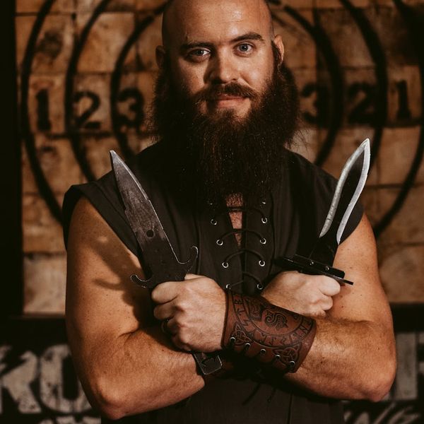 Man in a strong warrior yoga pose against a dark background.
